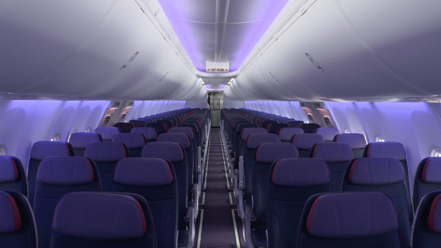 Empty airplane cabin with rows of blue seats, illuminated by soft purple lighting.