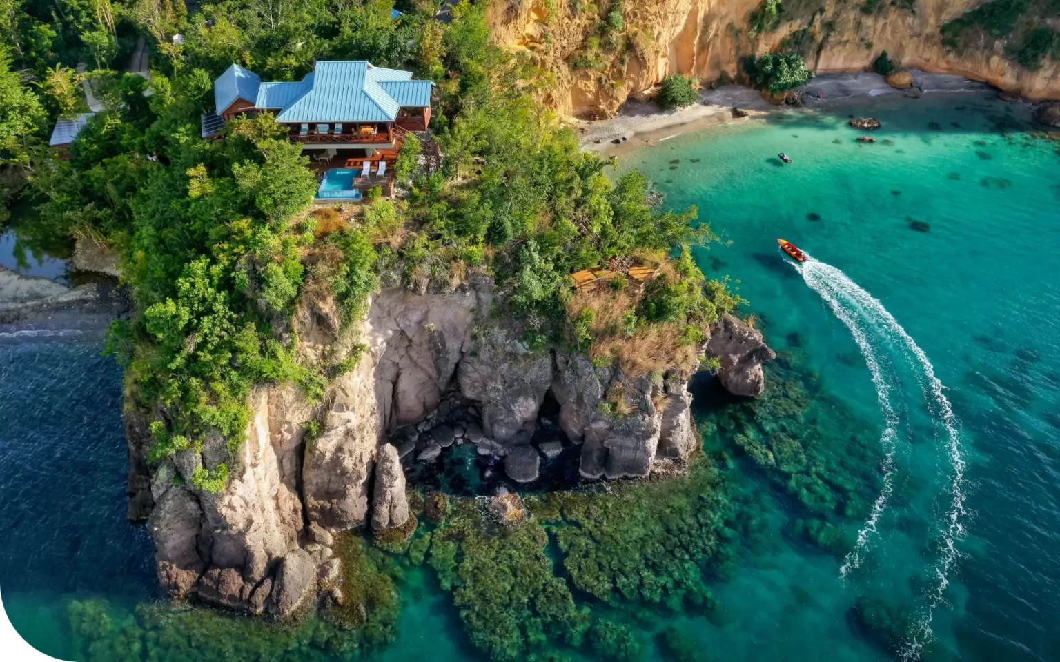 Coastal villa perched on a cliff surrounded by lush greenery, overlooking turquoise waters with a boat leaving a white wake.