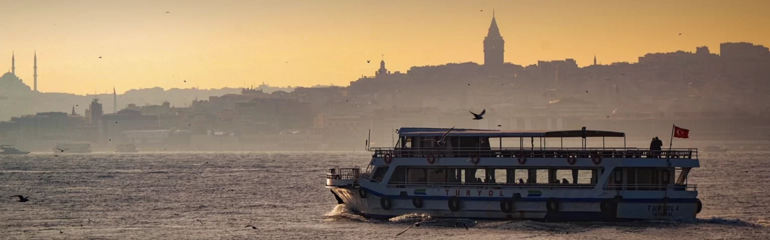 Ferry on the Bosphorus at sunset with Istanbul skyline in the background.