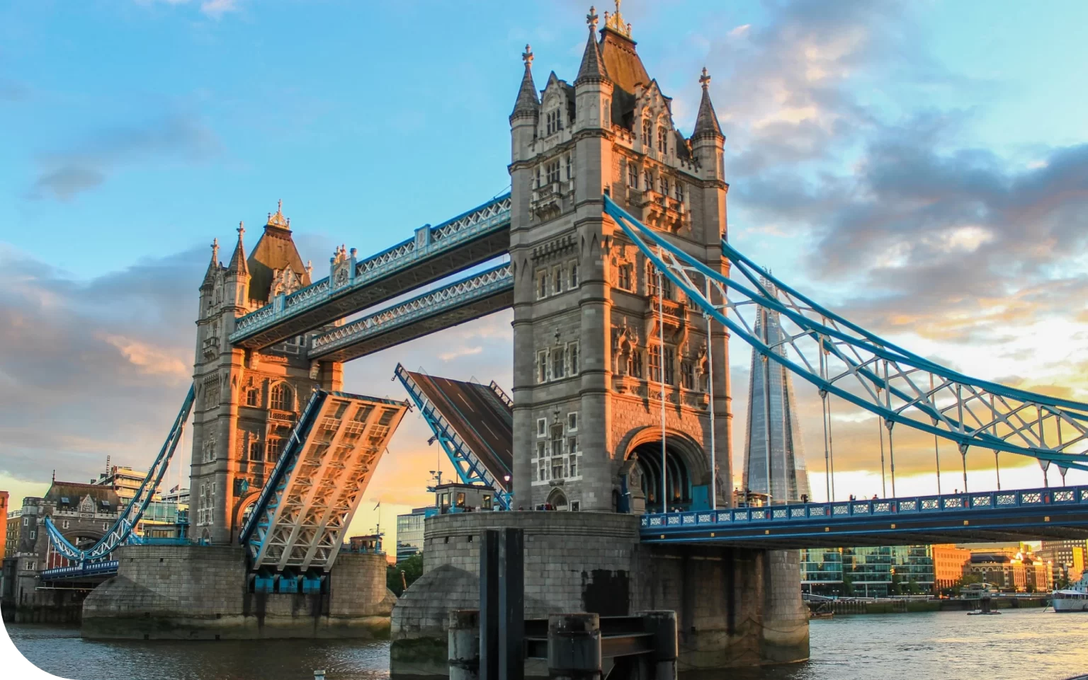 Tower Bridge in London with raised bascules at sunset.