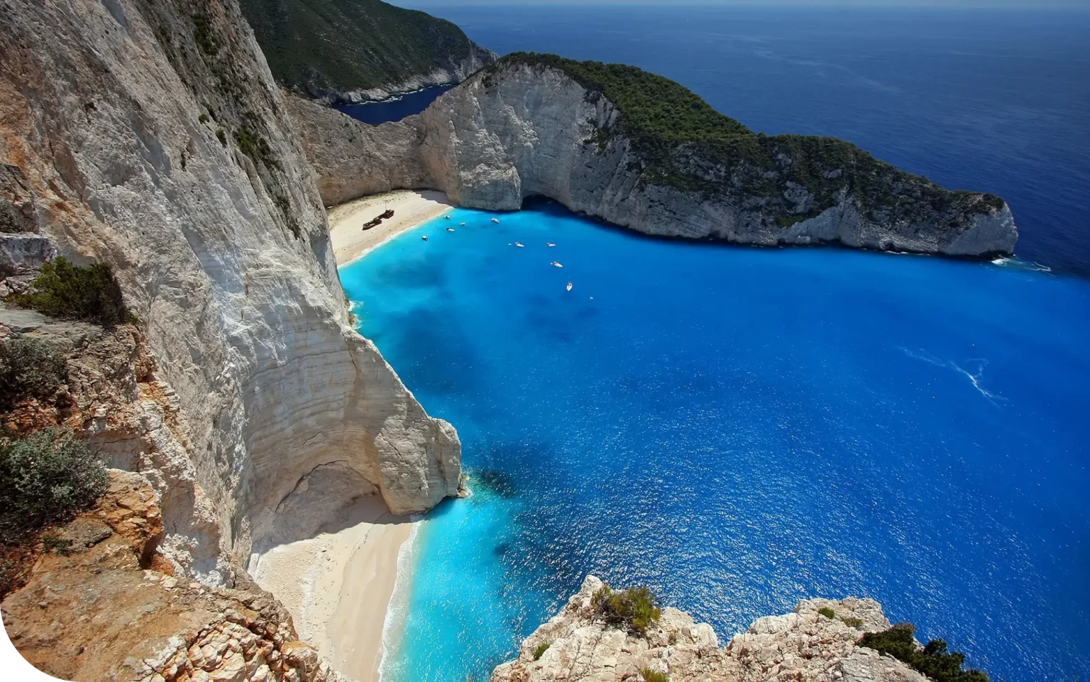Clear blue water in a secluded cove surrounded by white cliffs and lush greenery.